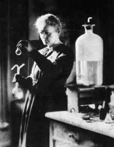 Marie Curie inspects a test tube in her lab